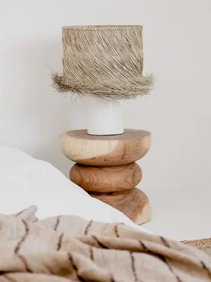 Lampe de salon boheme. Un lampe à poser avec pied en céramique blanche et abat-jour en sisal naturel. Posé sur un tabouret en bois tourné moderne. Design actuel, inspiration Bali, Marrakech. Ambiance méditerranéenne.